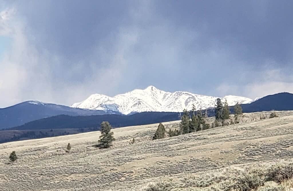 Snowy peaks rise above blue mountains and sagebrush hills.